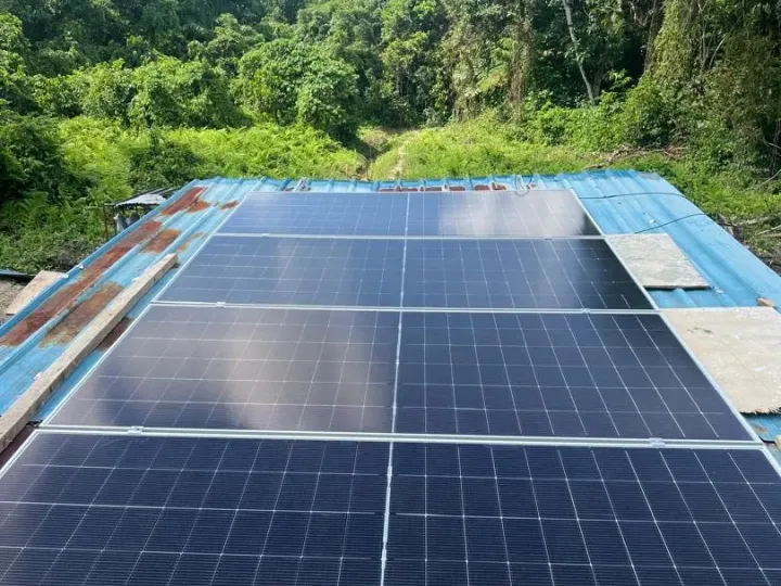 Solar panels on a roof at an off-grid site surrounded by forest in Sarawak